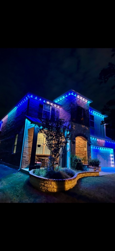 Blue roofline and garage lighting on a brick home