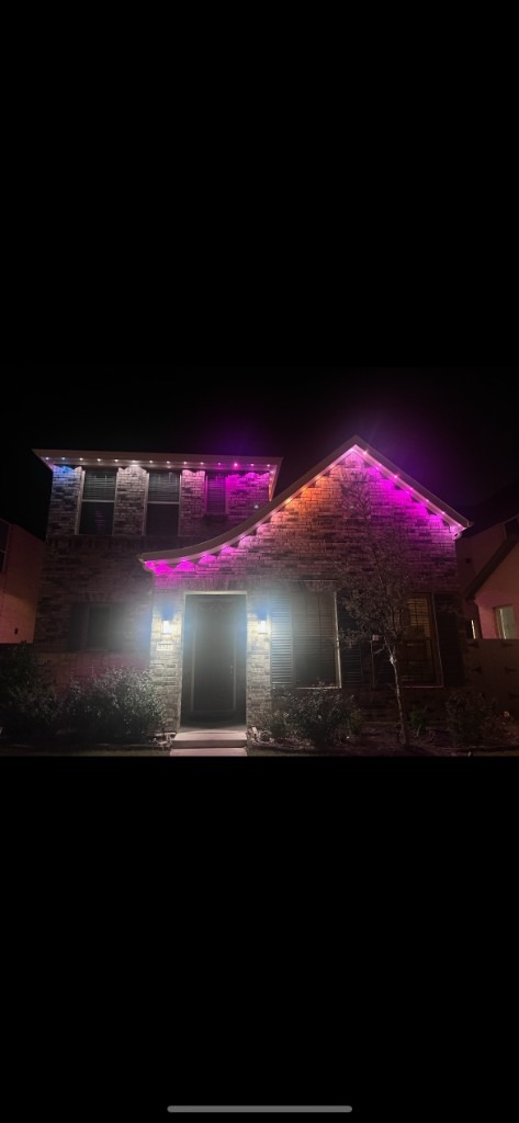Pink and white peak lighting on a brick house