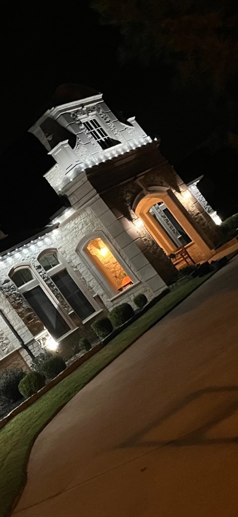 White roofline lights on a stone home with arched entry